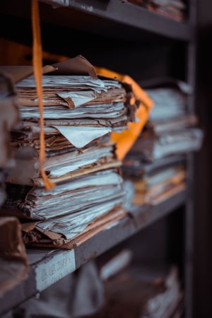 Stacks of old documents and papers piled on dusty shelves, creating an organized yet chaotic scene.